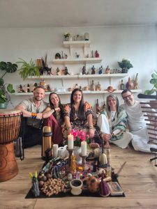 Ceremony guests sitting together around a candlelit cacao altar with flowers