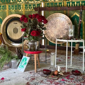 Ceremony space with gongs, red roses and a cacao altar scattered with petals